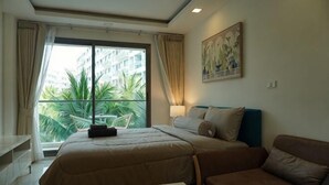 Une chambre d’hôtel avec un lit, un canapé, une fenêtre avec des rideaux et un tableau au mur.