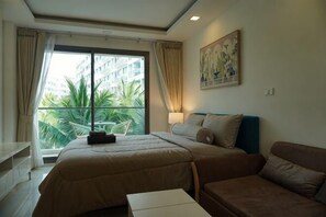 Ein Hotelzimmer mit Bett, Sofa, einem Fenster mit Vorhängen und einem Bild an der Wand.