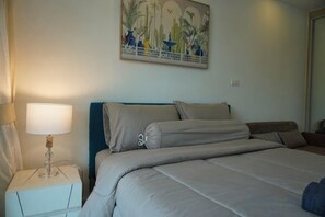 Un dormitorio con cama, mesita de noche, lámpara y un cuadro en la pared.