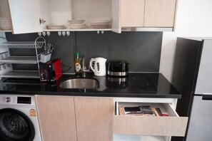 Una cocina compacta con un lavamanos, estufa y cafetera.