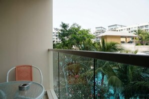 A balcony with a table and chair, overlooking a swimming pool and greenery. - Laguna beach resort Maldives 3 - Pool view studio in Pattaya jomtien (Pattaya)