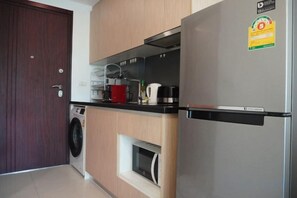 Une cuisine compacte équipée d’un lave-linge, d’un four encastré et d’un réfrigérateur.