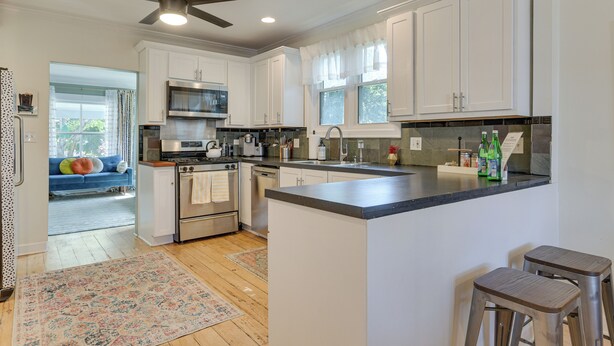 A modern kitchen with white cabinets, a central island, stainless steel appliances, and a ceiling fan. - Classic Forest Park Foursquare < 1 Mi to Blue Line (Forest Park)