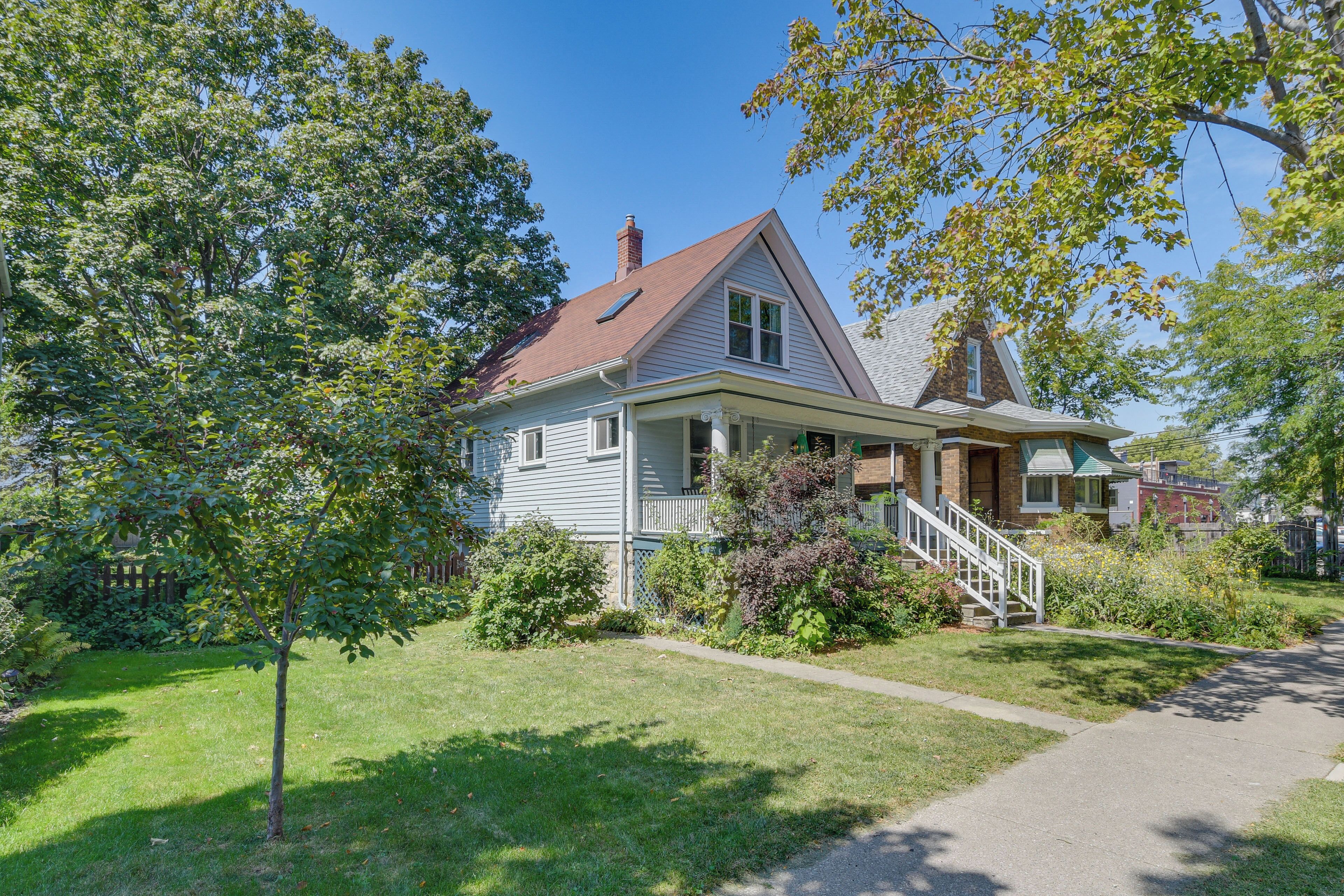A two-story house with a front porch, a chimney, and a small garden.