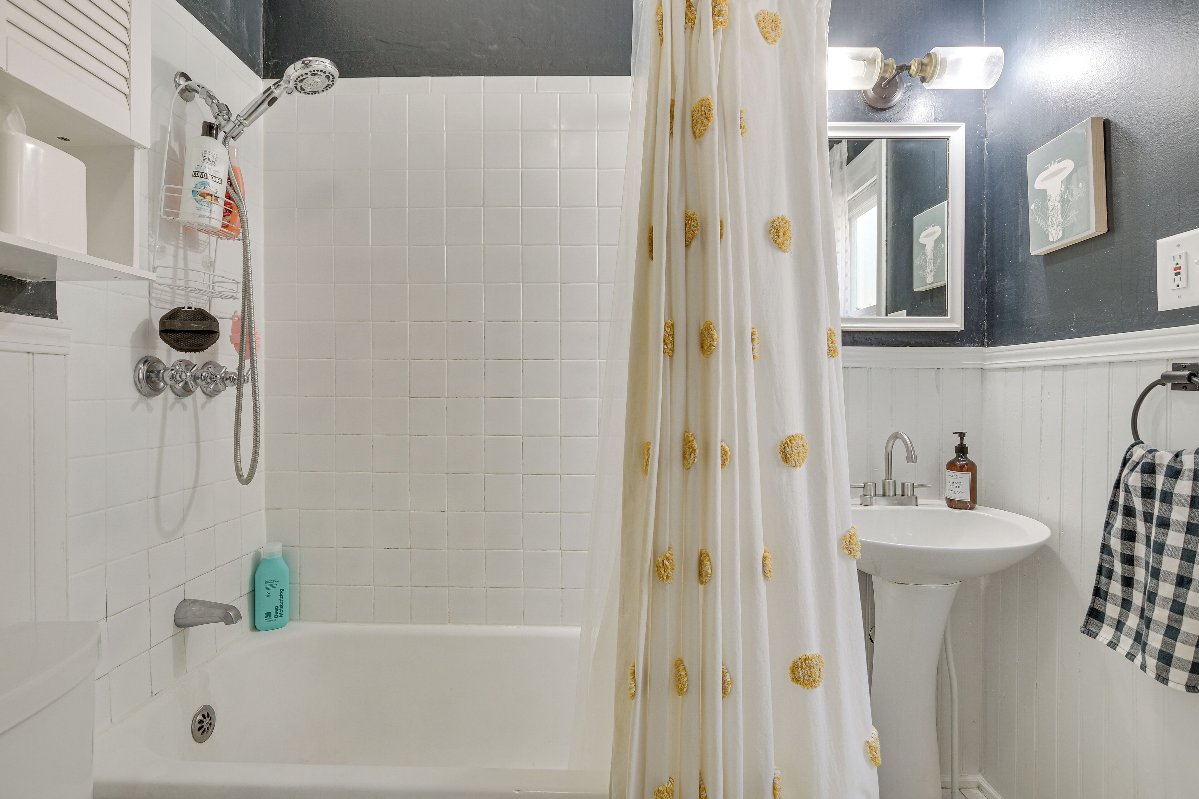Une salle de bain avec une baignoire, une douche, un lavabo et un miroir.