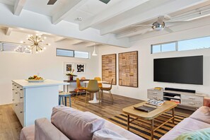 A modern living space with a dining area, a sofa, a coffee table, and a TV.