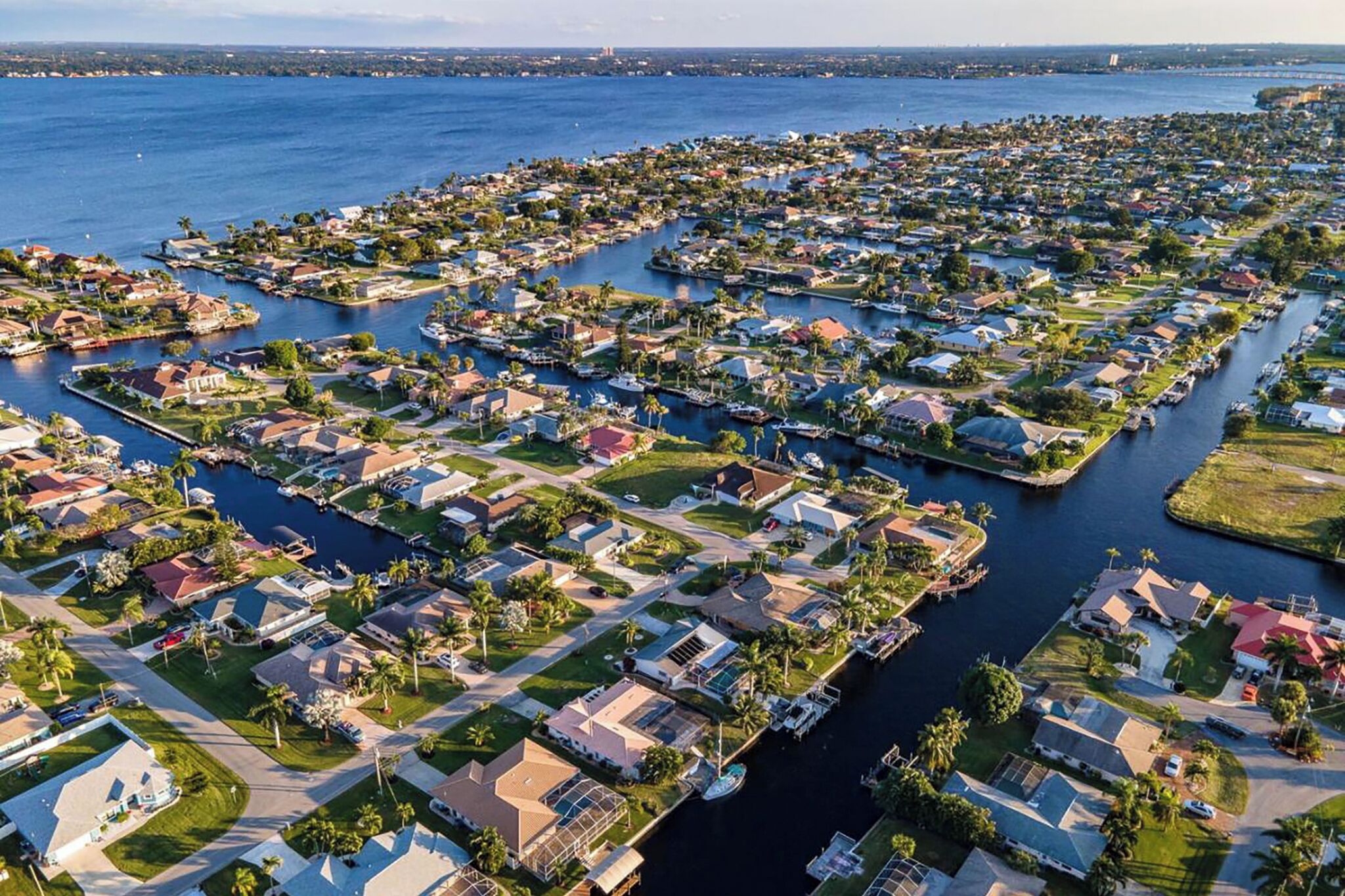 An aerial view of a residential area with houses arranged in a grid pattern along a waterfront.