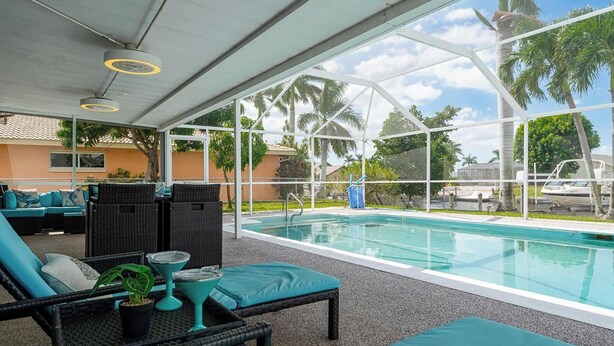 An indoor pool area with lounge chairs and a covered seating area. - Dock Your Boat: Waterfront Cape Coral Home w/ Pool (Cape Coral)