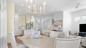 A modern kitchen with a dining area, featuring a chandelier, white cabinetry, and a round dining table with chairs. - Beachside Haven w/ Firepit, BBQ & Pool Access | Driftwood Dreams by AvantStay (Inlet Beach)