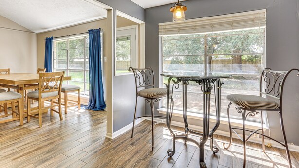 A dining area with a wooden table and chairs, a metal bar stool, and a hanging light fixture. - Fish, Golf, Explore: Home 3 Mi to Prien Lake Park! (Lake Charles)