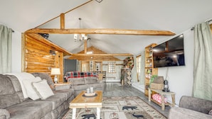 A cozy log cabin interior with a sofa, a wooden coffee table, and a patterned rug. - Water's Edge Retreat on Butternut Lake! (Butternut)