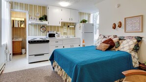 Un dormitorio pequeño con cama, kitchenette y baño.