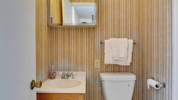 A bathroom with a wooden vanity, a sink, a toilet, a towel rack, and a mirror.