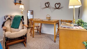 Una habitación acogedora con una silla mullida, una mesa de madera y una lámpara.