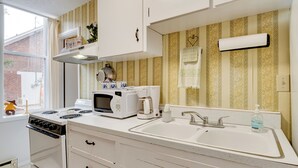 Una cocina con estufa, microondas, cafetera y pileta.