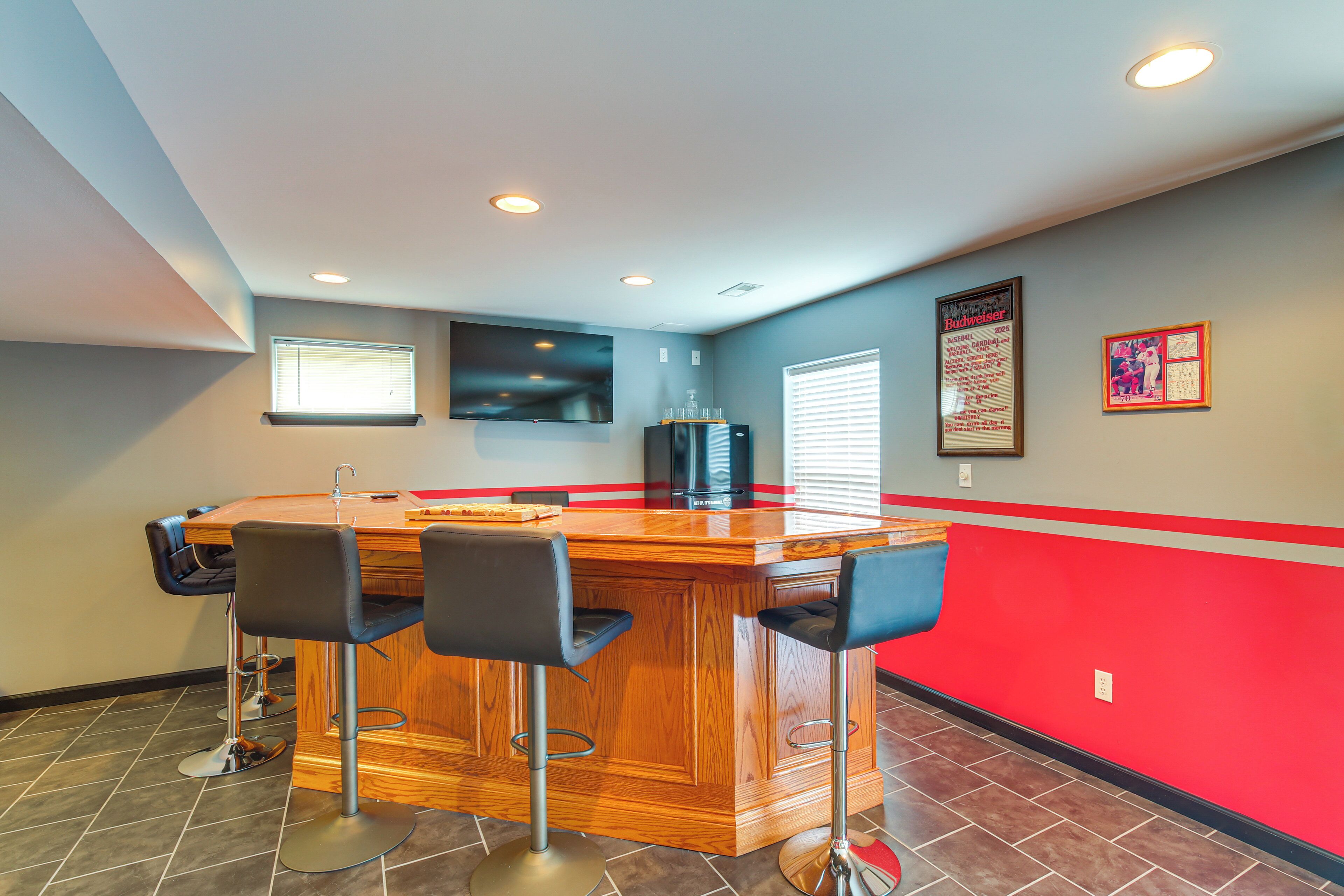 A bar area with a wooden counter and three black bar stools.