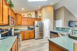 Una cocina moderna con armarios de madera, electrodomésticos de acero inoxidable y una encimera de granito verde.