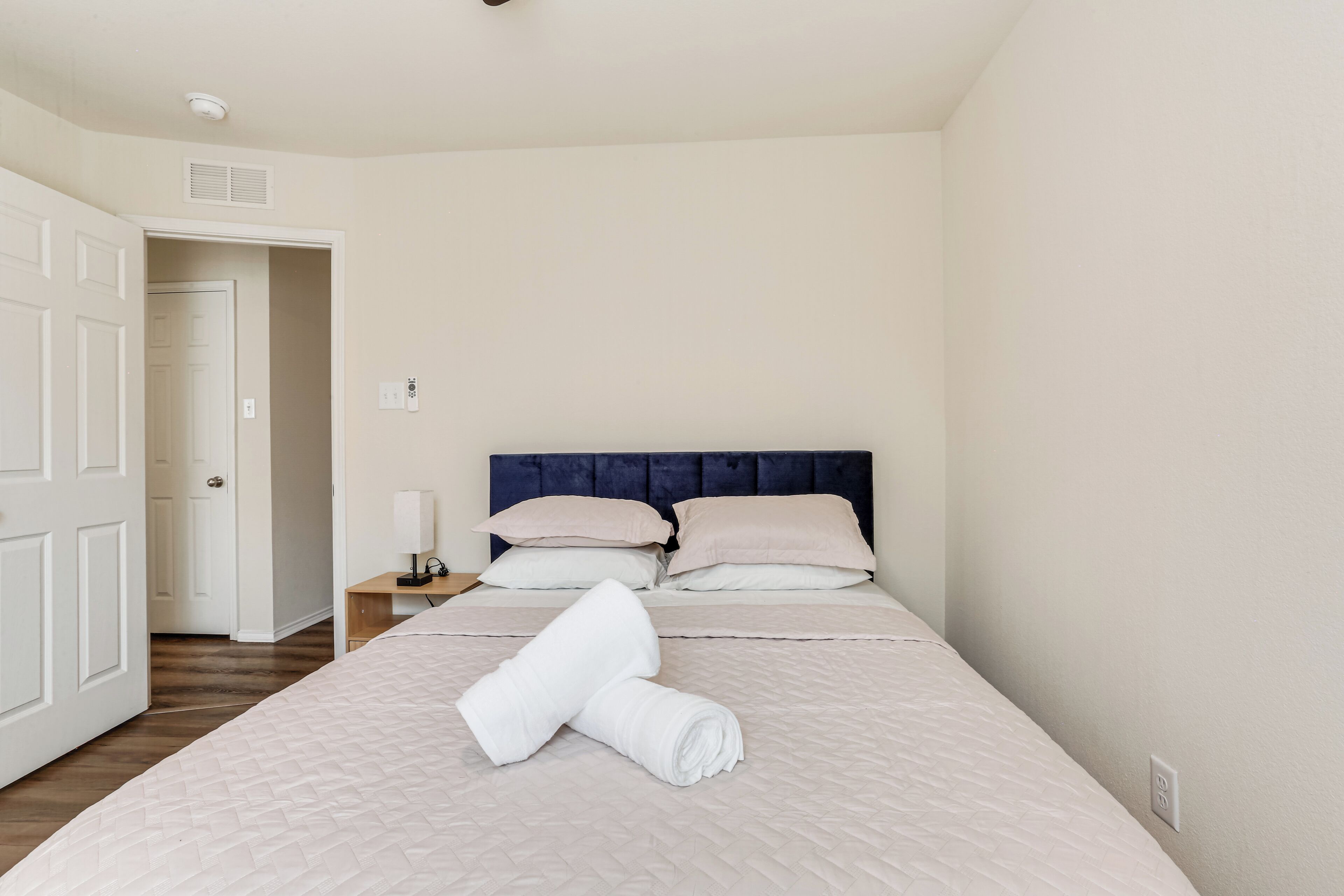 Une chambre d’hôtel avec un lit, une table de chevet, une lampe et une porte donnant sur une autre pièce.