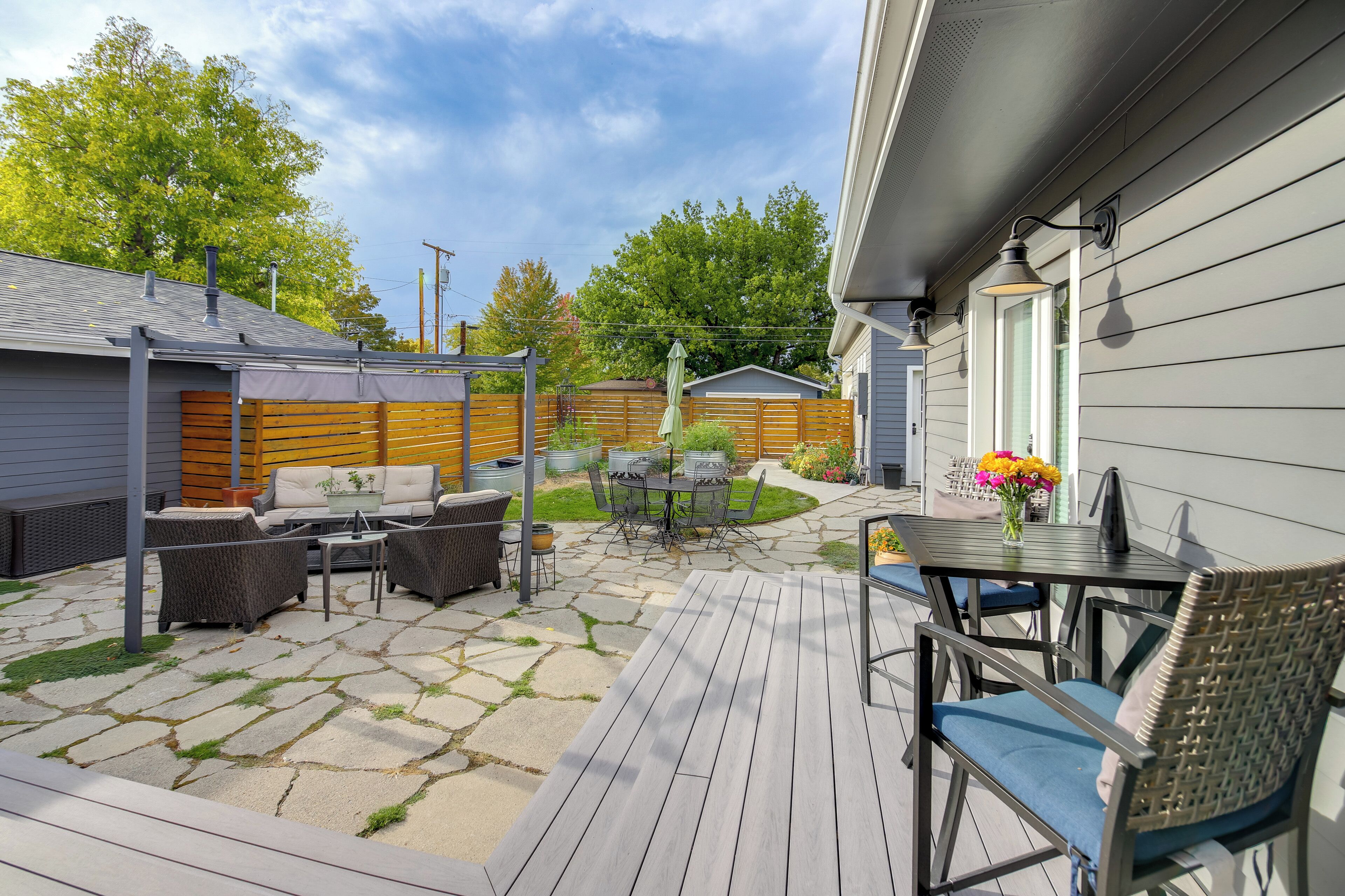 A patio area with a wooden deck, outdoor furniture, and a small table with a vase of flowers.