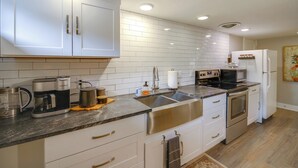 Une cuisine moderne avec des armoires blanches, des appareils en acier inoxydable et un comptoir en granit.