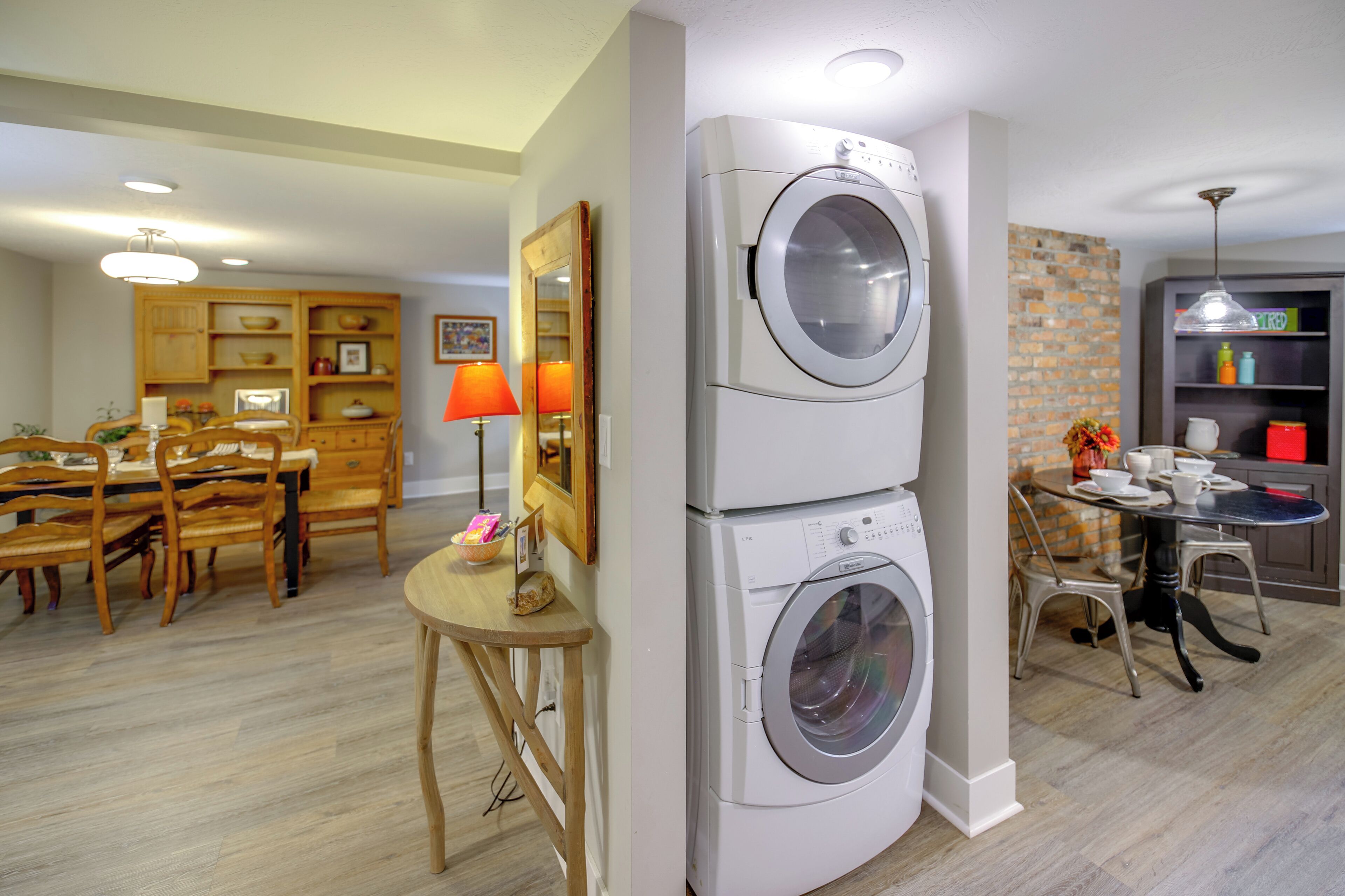 Une cuisine compacte équipée d’un lave-linge et d’un sèche-linge intégrés, d’une table à manger en bois et d’une petite table ronde avec des chaises.