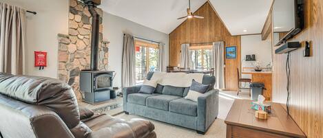 Una sala acogedora con chimenea de piedra, un sofá, una mesa de centro y un televisor.