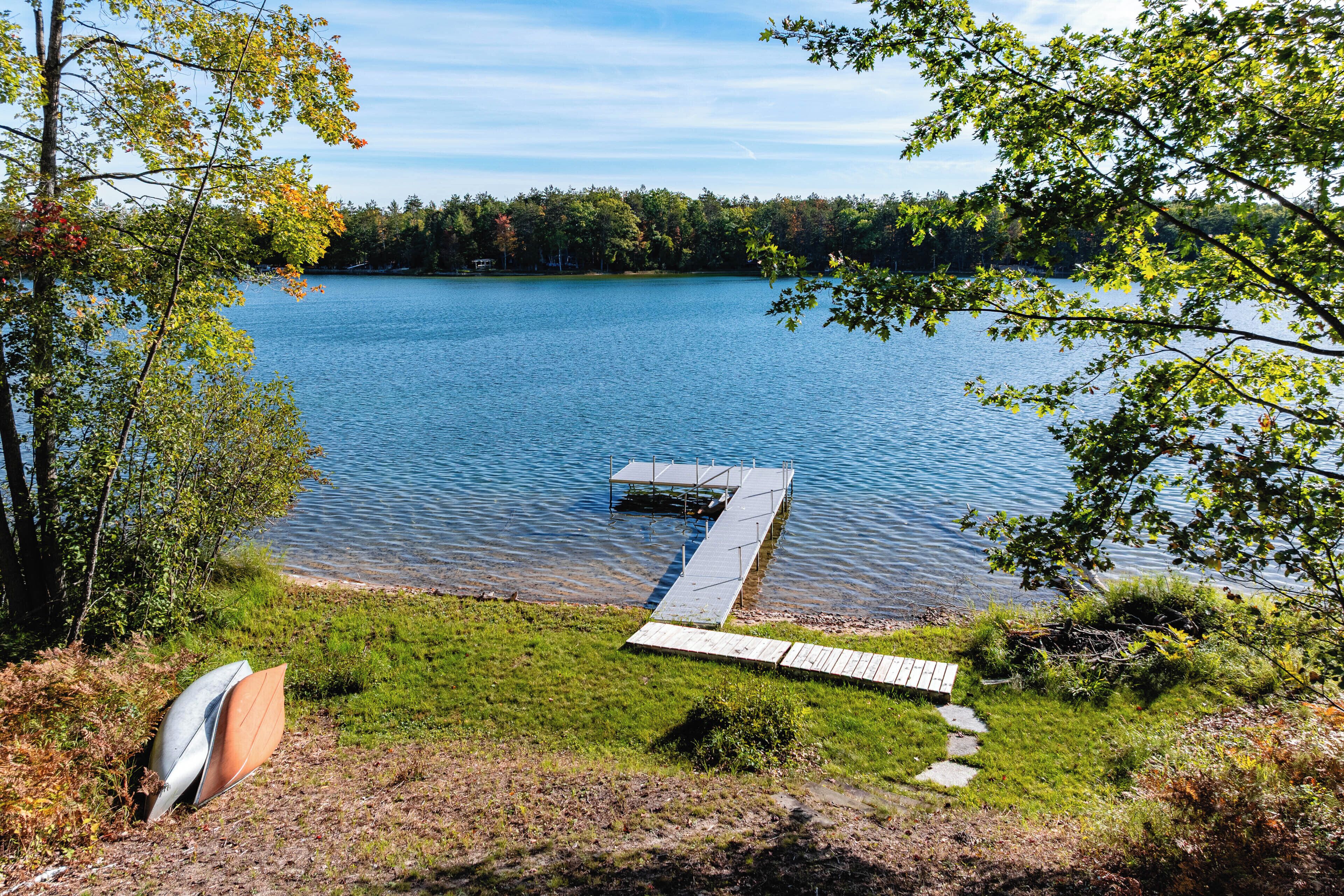 A lakeside dock with a grassy area and trees.