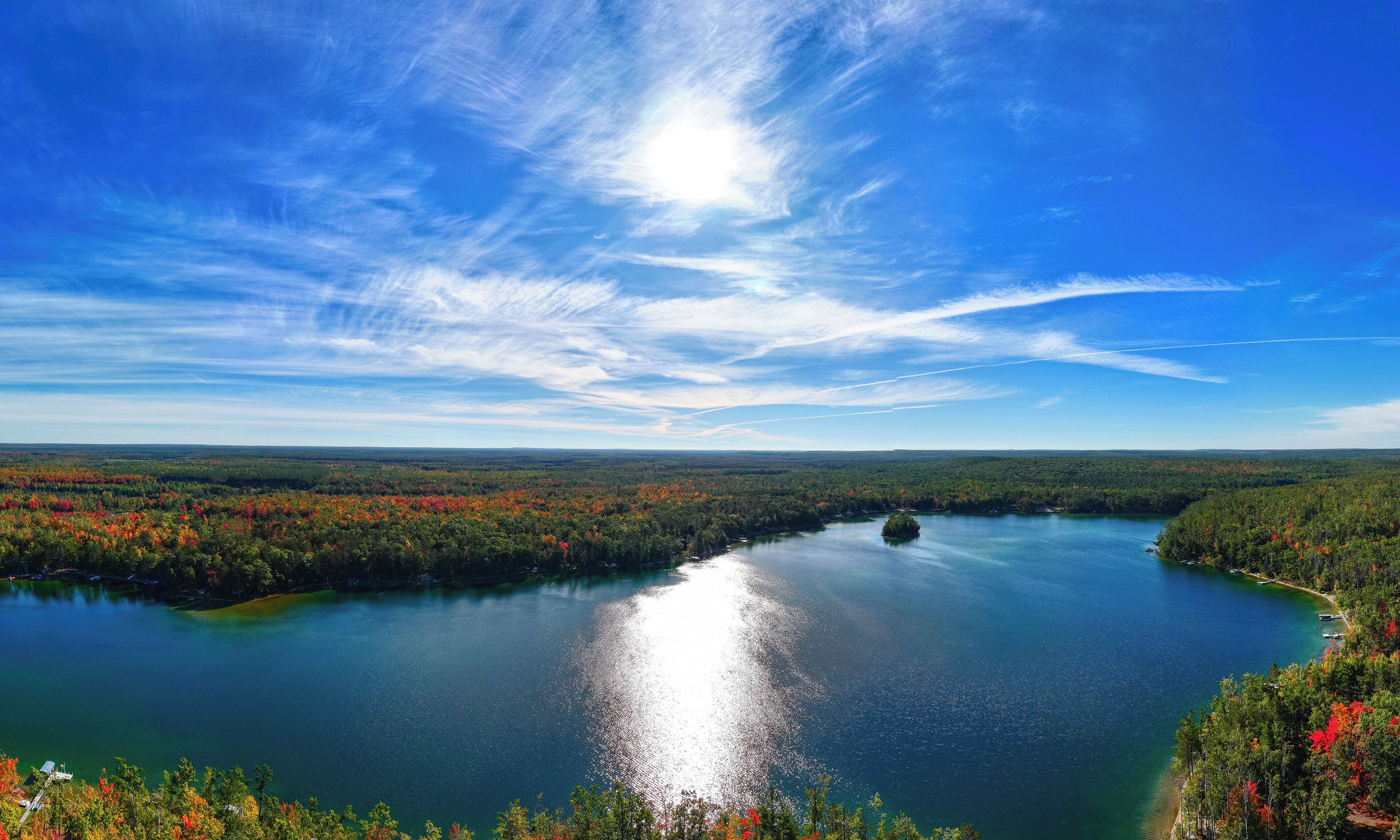 A lake surrounded by forested hills with a clear sky.