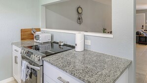 Une cuisine dotée de plans de travail en granit, d’un four à micro-ondes, d’un four traditionnel et d’une horloge murale.
