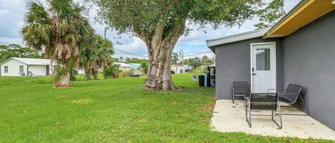 A residential property with a large tree, a patio with chairs, and a garage.
