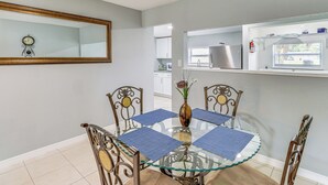Un coin repas avec une table en verre, des chaises en métal et des sets de table bleus.