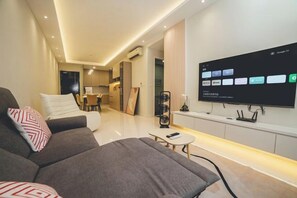 Una sala de estar moderna con un sofá, una mesa de centro y un televisor de pantalla plana montado en la pared mostrando una interfaz de hogar inteligente.
