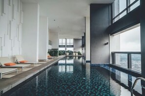 Ein Innenpool mit Infinity-Kante und freiem Blick auf die Stadt durch große Fenster.