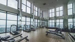 A spacious gym with large windows, treadmills, and weight machines. - Sky88 Residence Johor Bahru (Johor Bahru)