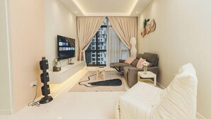 A modern living room with a sofa, a TV, and a large window with curtains. - Sky88 Residence Johor Bahru (Johor Bahru)