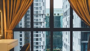 A hotel room with a large window, a bed, a bedside table, and a chair. - Sky88 Residence Johor Bahru (Johor Bahru)