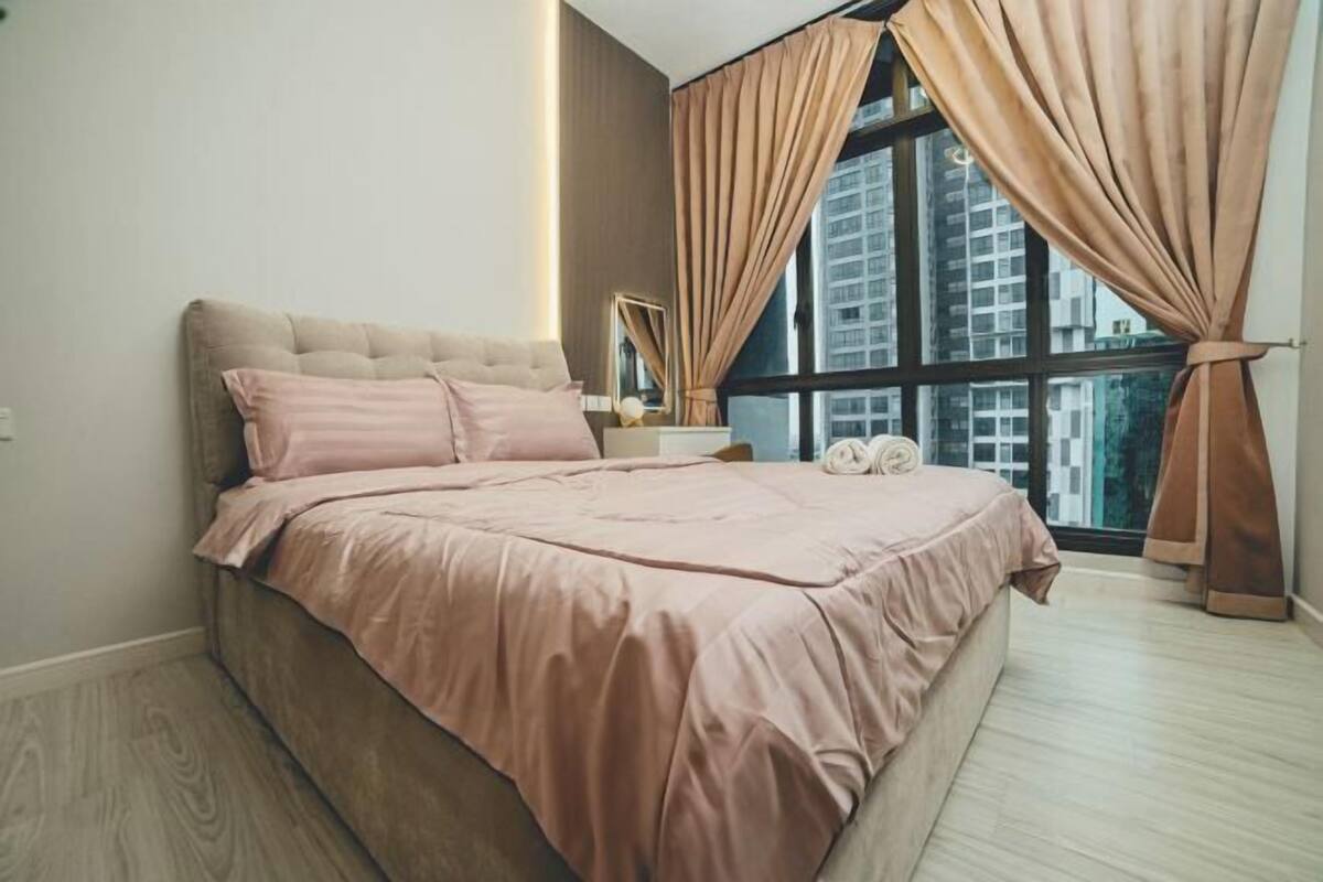 Un dormitorio con una cama grande, una mesita de noche, un espejo y una ventana con cortinas.