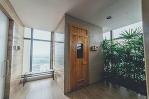 Un interior moderno con puerta de madera, ventanas amplias y plantas de interior.