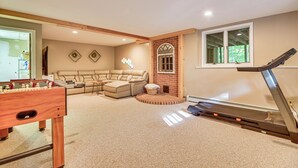 A spacious living room with a foosball table, a treadmill, and a large sectional sofa. - Hike, Leaf-peep, Ski: Hideaway w/ Private Hot Tub! (Intervale)