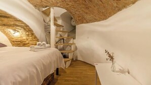 A cozy room with a bed, a small table with a vase, and a spiral staircase. - Stay in a real medieval tower (lower floors) (Tallinn)