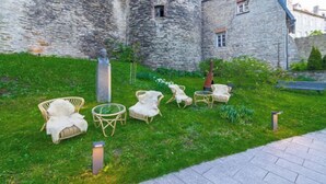 A courtyard with stone walls, wicker furniture, and a small tree. - Stay in a real medieval tower (lower floors) (Tallinn)