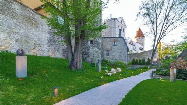 A stone building with a tower, surrounded by greenery and a paved pathway. - Stay in a real medieval tower (lower floors) (Tallinn)