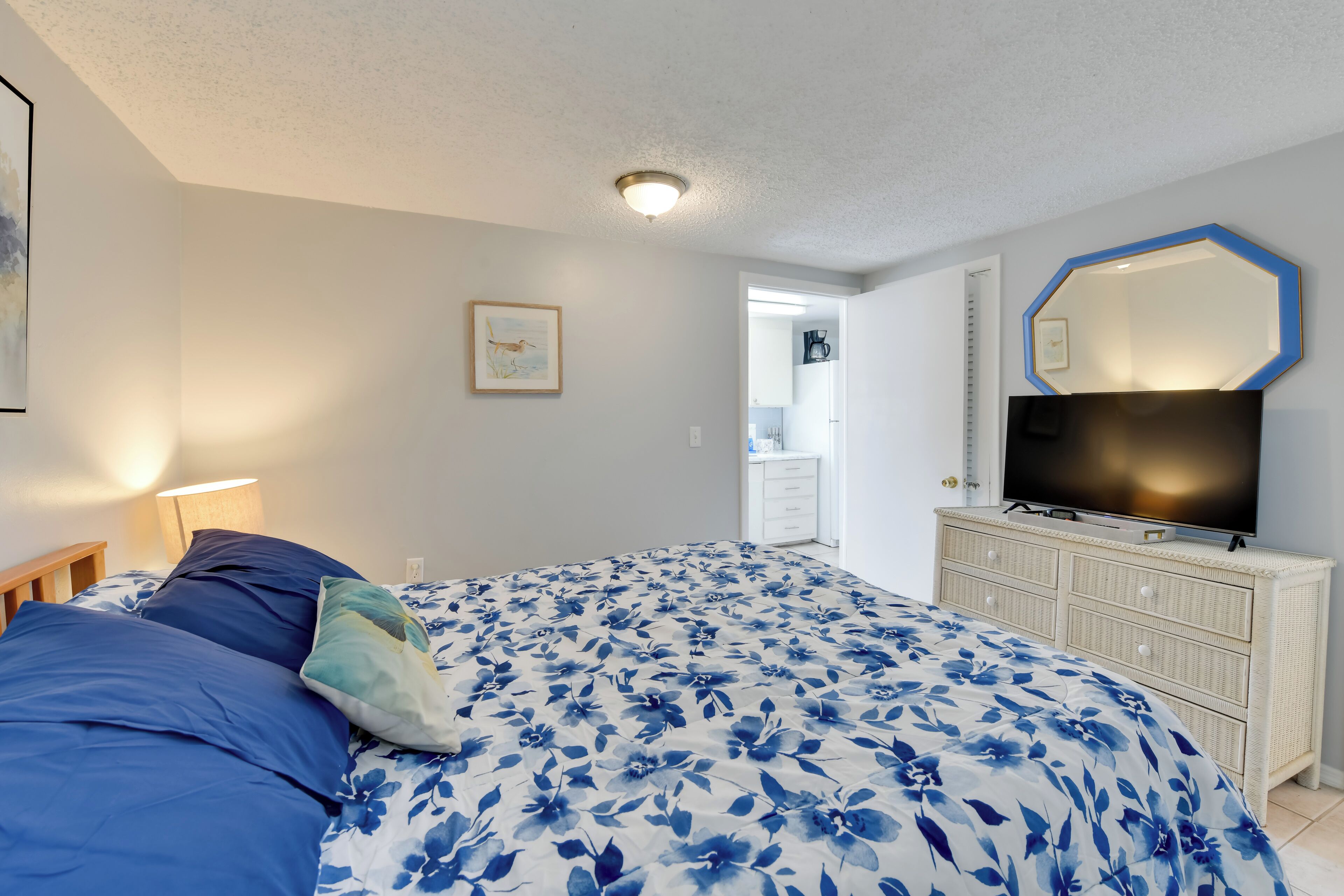 Une chambre à coucher avec un lit, une télévision, une commode et un tableau encadré au mur.
