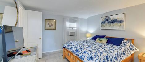 Un dormitorio con cama de madera, cómoda blanca, espejo y un cuadro en la pared.