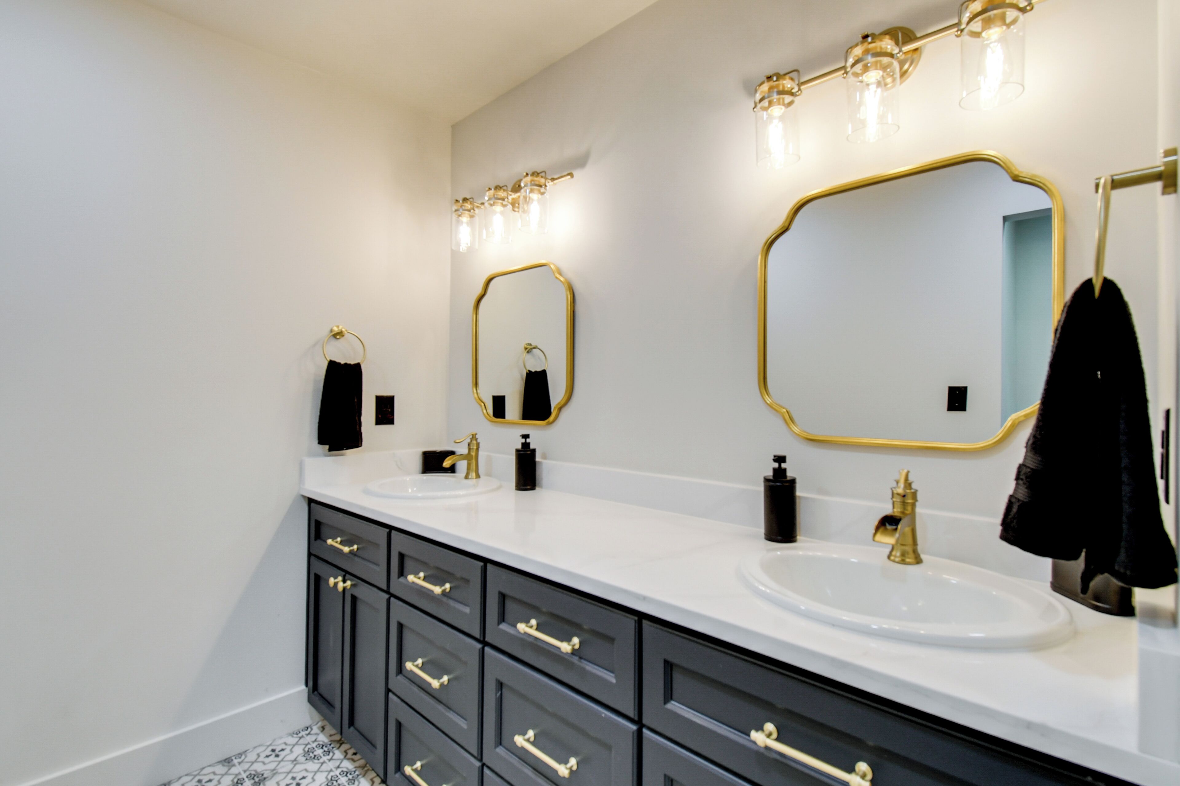 A bathroom with two sinks, black and gold fixtures, and a large mirror.