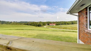Blick vom Balkon auf ein grünes Feld und ein rotes Gebäude in der Ferne.
