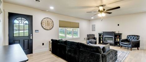 A spacious living room with a black sofa, a fireplace, and a ceiling fan.