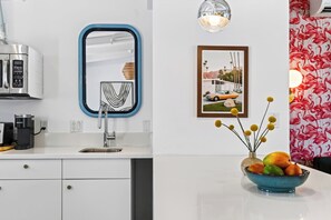 Una cocina moderna con microondas integrado, un lavabo y una cafetera.