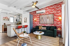 Una sala de estar moderna con un sofá verde, una mesa de centro redonda y un comedor con sillas rojas.
