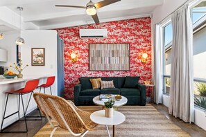 A modern living room with a green sofa, a round coffee table, and a wicker chair.